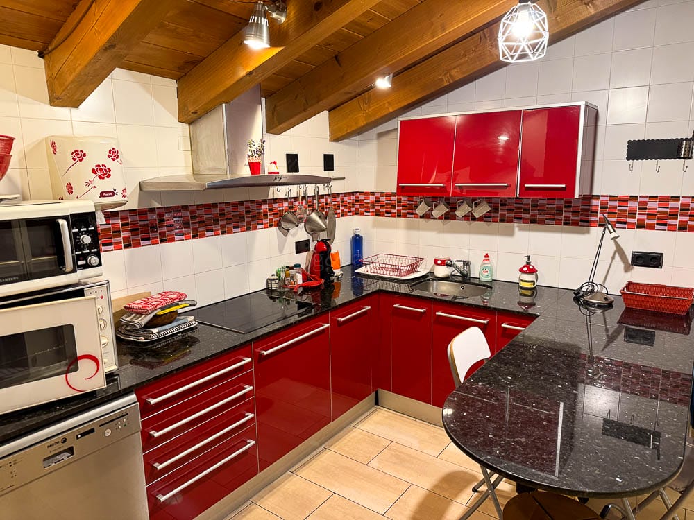 Cuina de Cal Marinall amb rentavaixelles, forn, microones, armaris i una taula amb taburets